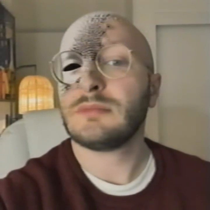 A frame from Generation Loss: a half converted face wearing glasses.